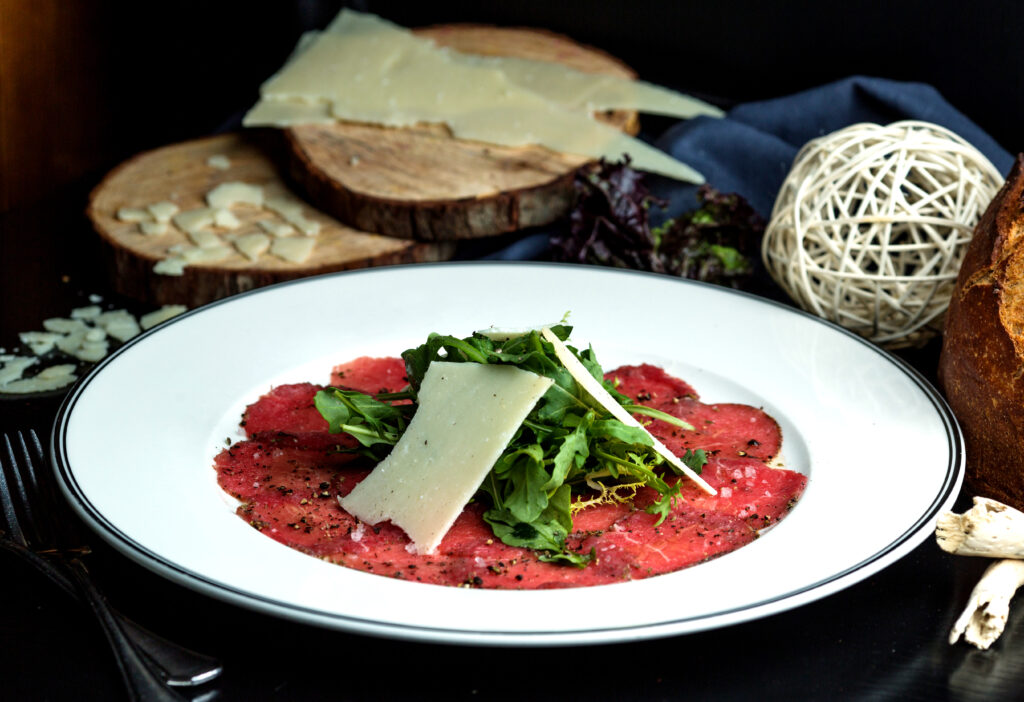 carpaccio slices topped with arugula and parmesan slice